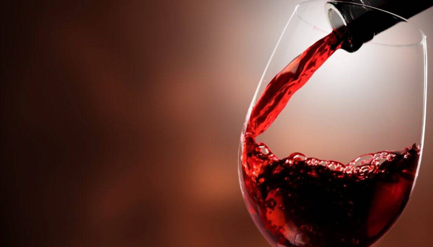 Red wine pouring in glass on  background